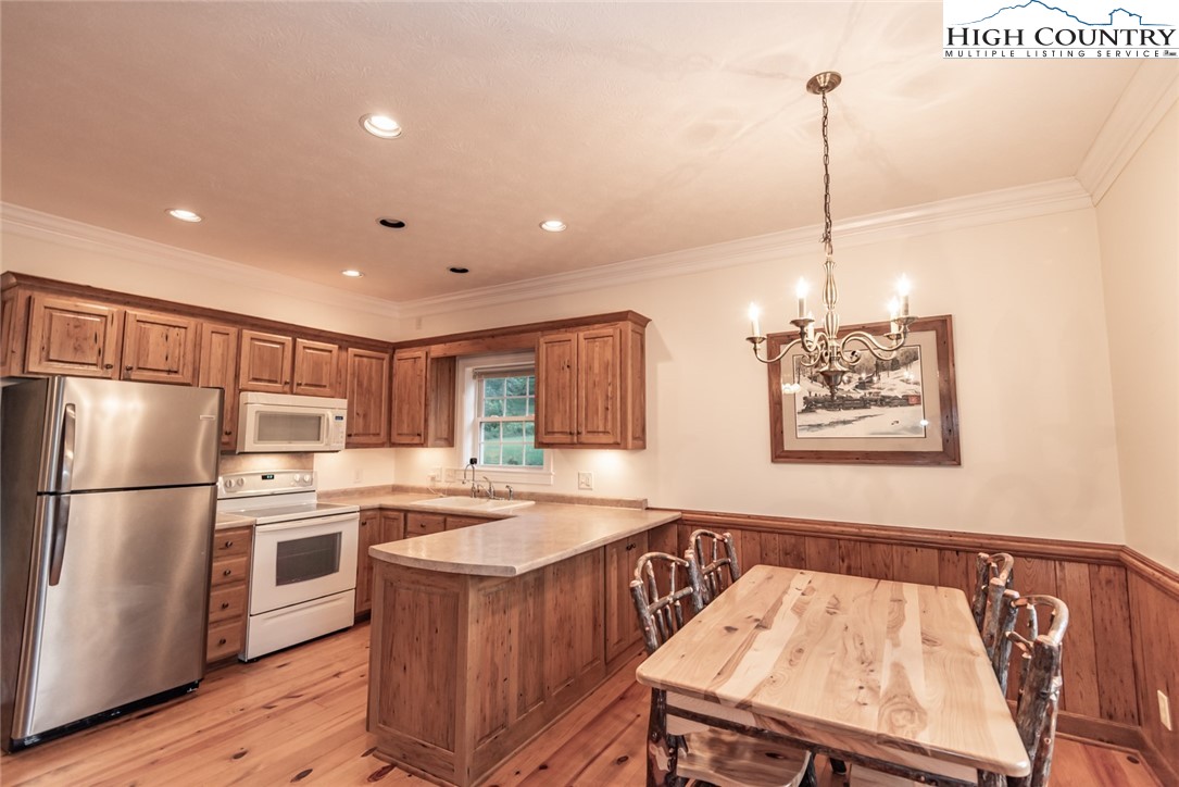 1195 Long Branch Road Lansing, NC 28643 - Photo 2 of 31 a kitchen with kitchen island a refrigerator a stove a sink and a wooden floor