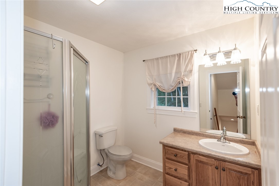 1195 Long Branch Road Lansing, NC 28643 - Photo 27 of 31 a bathroom with a granite countertop sink toilet a mirror a vanity and shower