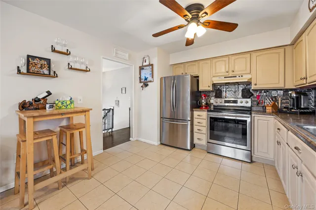 a kitchen with stainless steel appliances a stove a refrigerator cabinets and a dining table