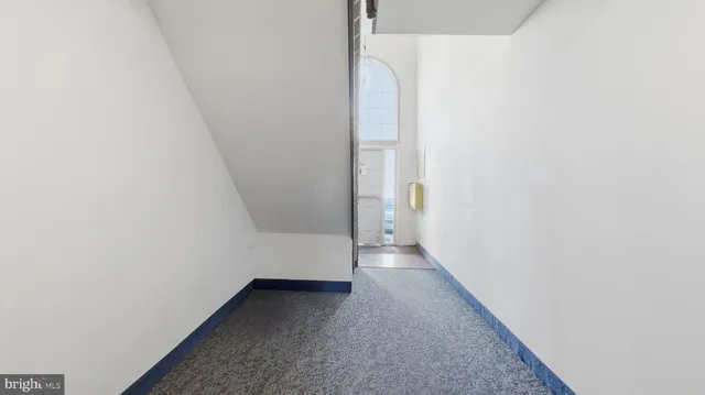 a view of a hallway with wooden floor and a bathroom