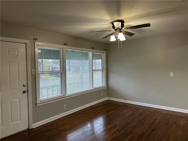 a view of a livingroom with a fan a large window with wooden floor