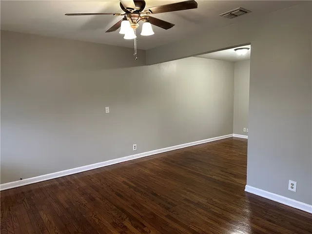 an empty room with wooden floor and fan