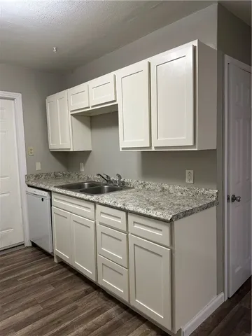 a kitchen with granite countertop cabinets stainless steel appliances and a wooden floor