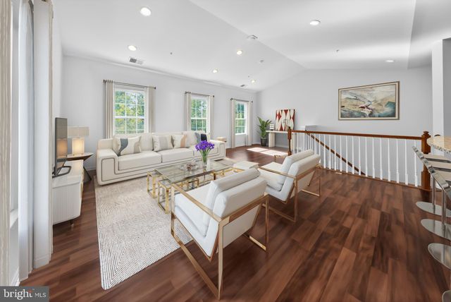 a view of a living room with wooden floor and an empty kitchen