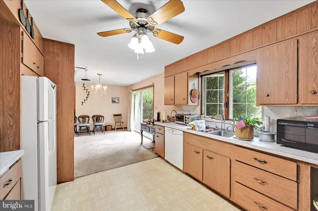 a large white kitchen with granite countertop a large window appliances and cabinets