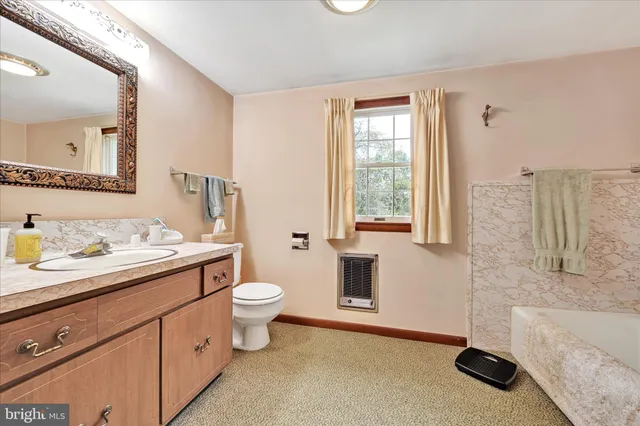 a bathroom with a granite countertop sink mirror vanity and toilet