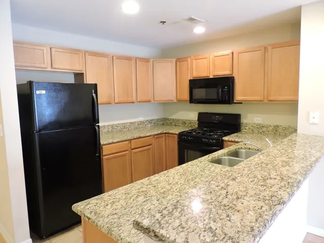 a kitchen with granite countertop a refrigerator a stove a sink a microwave and cabinets