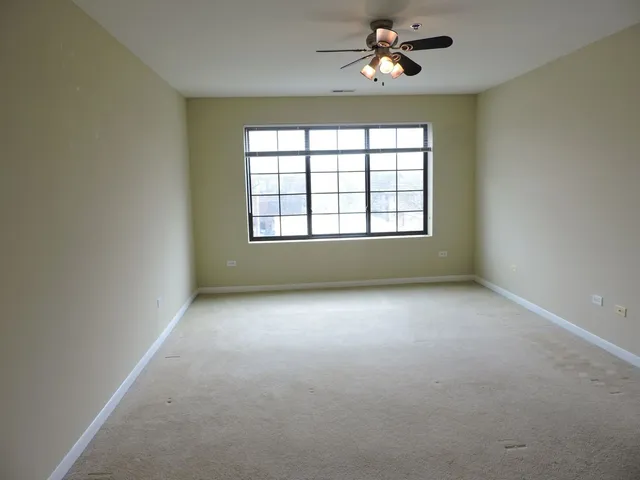 an empty room with chandelier fan and windows