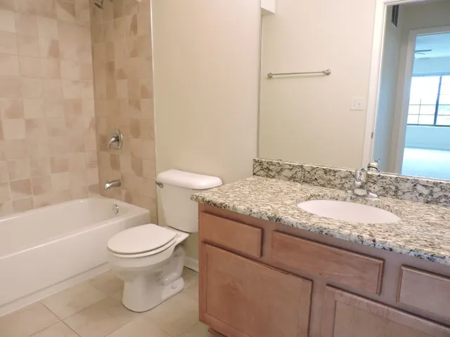 a bathroom with a granite countertop toilet sink and mirror