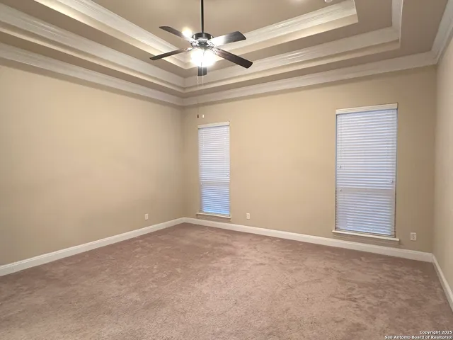 an empty room with a chandelier fan and windows