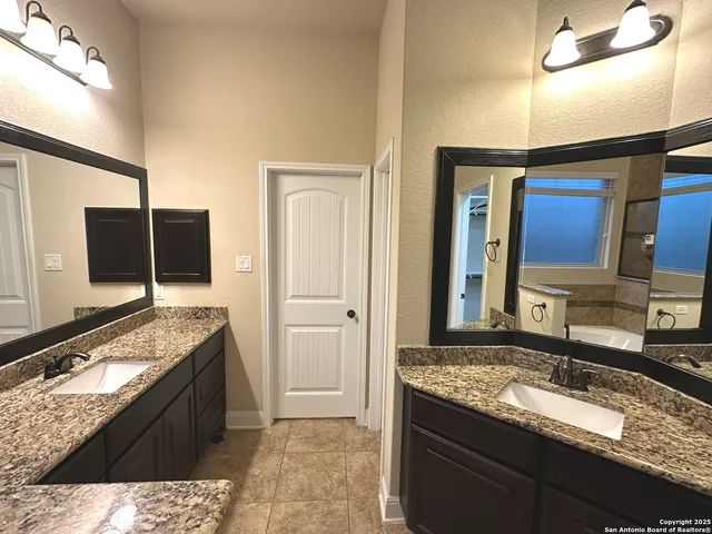 a bathroom with a granite countertop double vanity sink and mirror