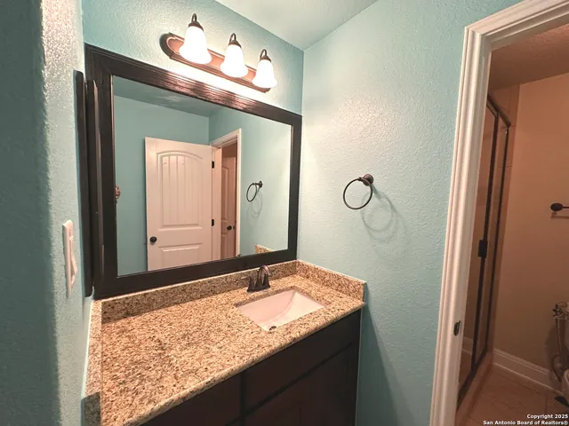 a bathroom with a granite countertop sink and a mirror
