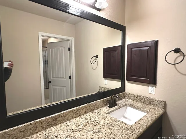 a bathroom with a granite countertop sink and a mirror