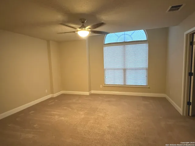 an empty room with windows and fan