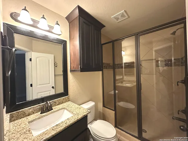 a bathroom with a granite countertop sink toilet mirror and shower