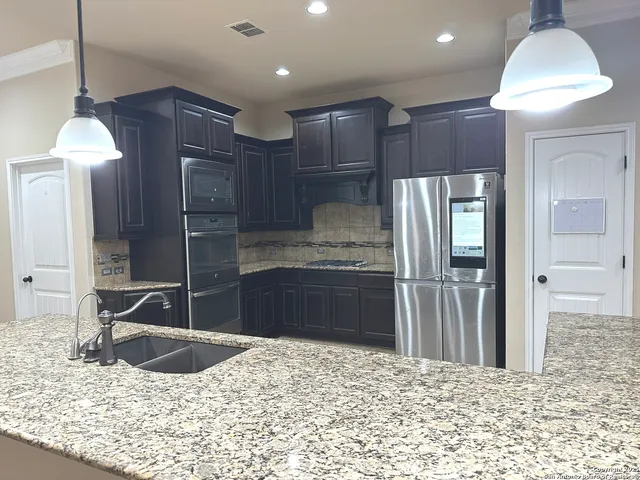 a kitchen with kitchen island granite countertop a refrigerator and a sink
