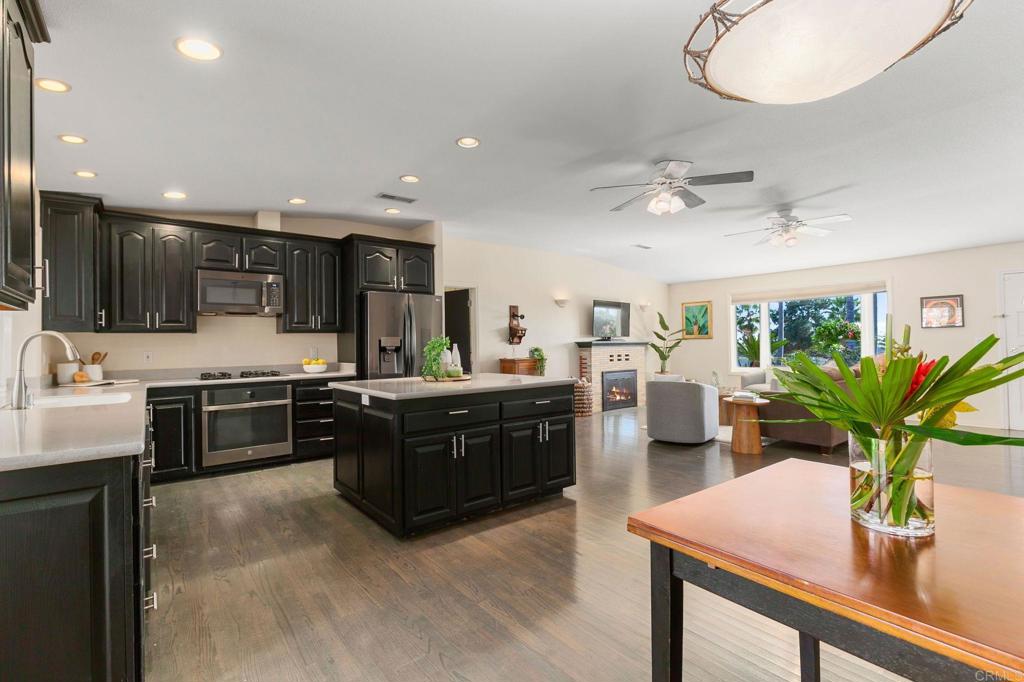 3326 Monroe Street Carlsbad, CA 92008 - Photo 17 of 63 a kitchen with stainless steel appliances kitchen island granite countertop a refrigerator a sink dishwasher a stove a dining table and chairs with wooden floor