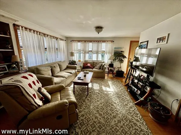 a living room with furniture a flat screen tv and a large window