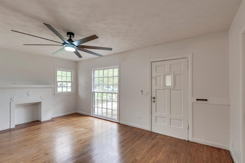 617 Wilson Street Lancaster, TX 75146 - Photo 5 of 30 an empty room with wooden floor ceiling fan and windows