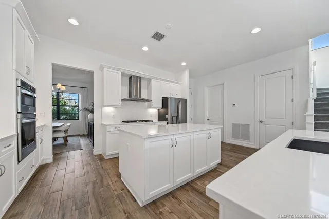 a kitchen with white cabinets a sink dishwasher and a stove with wooden floor