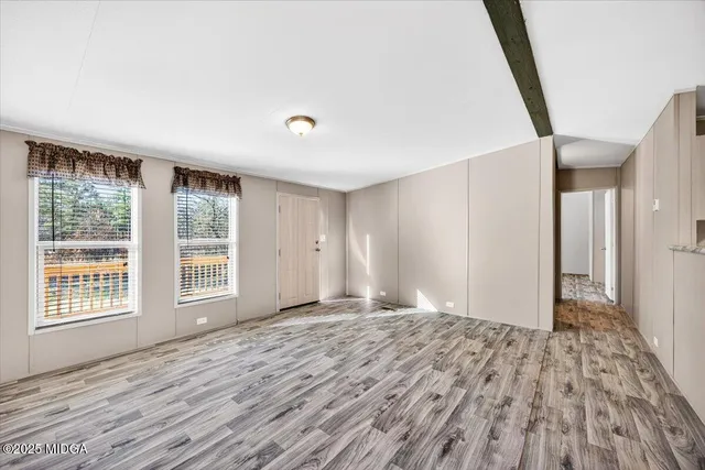 a view of an empty room with wooden floor and a window