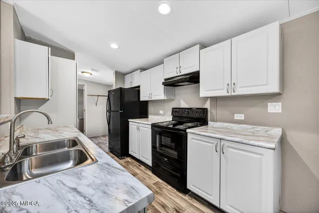 a kitchen with stainless steel appliances granite countertop a sink stove refrigerator and cabinets