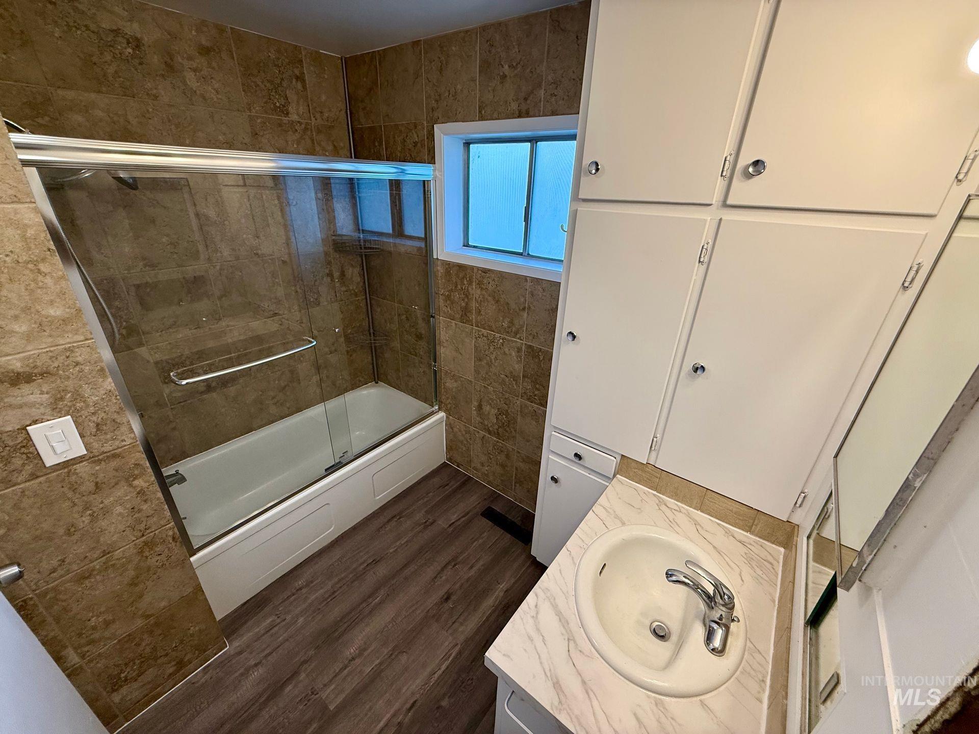 517 12th Street Clarkston, WA 99403 - Photo 5 of 16 Bathroom with vanity, tile walls, enclosed tub / shower combo, and dark wood-style floors