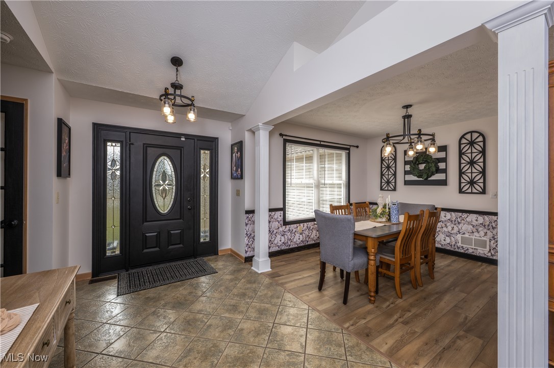 847 Lockwood Road Barberton, OH 44203 - Photo 10 of 29 Foyer featuring ornate columns, a textured ceiling, lofted ceiling, and an inviting chandelier