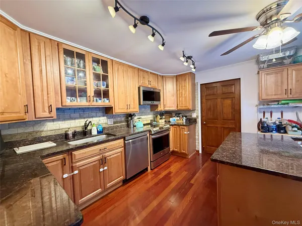 a kitchen with granite countertop wooden floors stainless steel appliances a window and a counter space
