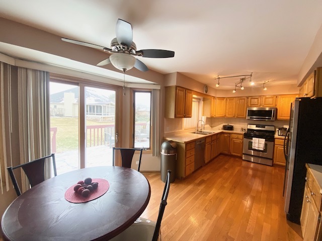 1702 Elm Street Spring Grove, IL 60081 - Photo 9 of 30 a kitchen with stainless steel appliances kitchen island granite countertop a stove a refrigerator a dining table and chairs with wooden floor