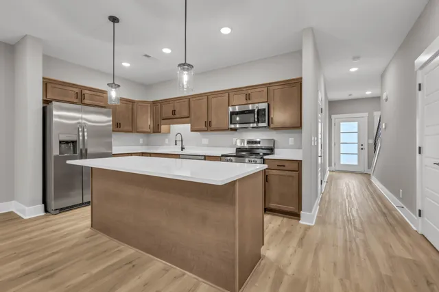 a kitchen with stainless steel appliances granite countertop a sink a stove top oven a refrigerator with wooden floors