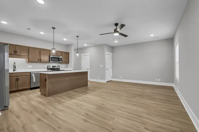 a large kitchen with stainless steel appliances granite countertop a stove a refrigerator a oven and a sink with large countertops