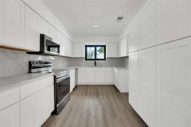 a kitchen with stainless steel appliances a stove a sink and a microwave