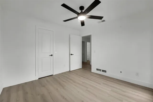 an empty room with wooden floor and ceiling fan