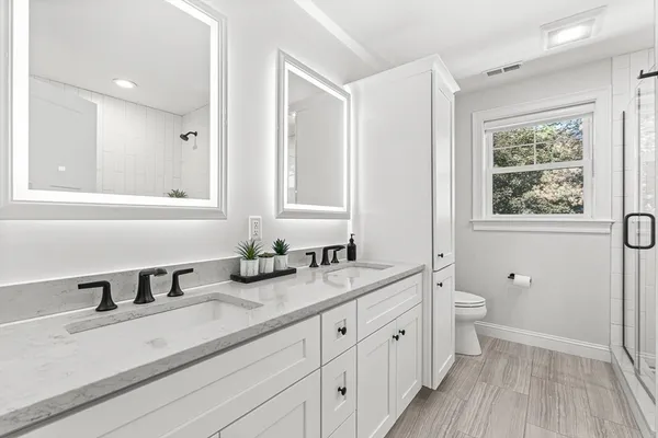 a bathroom with double vanity sink a mirror and a shower