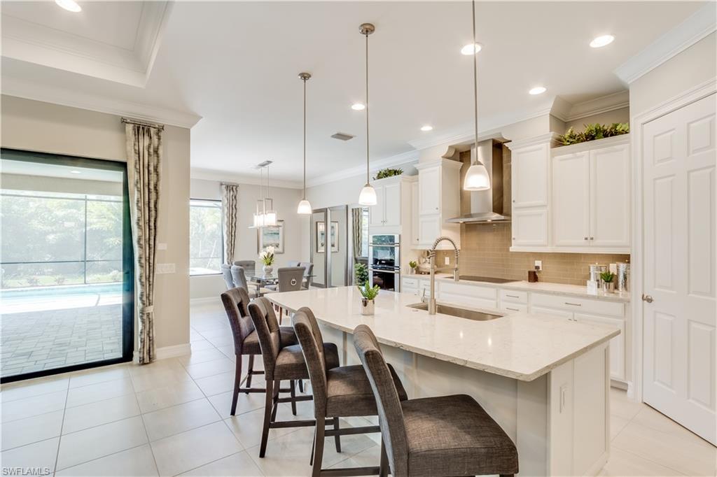 1423 Mockingbird Drive Naples, FL 34120 - Photo 7 of 26 a kitchen with kitchen island a dining table chairs and white cabinets