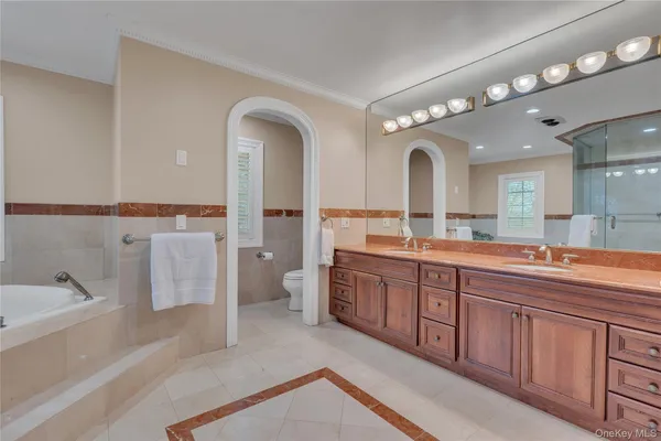 a spacious bathroom with a double vanity sink a mirror and a bathtub