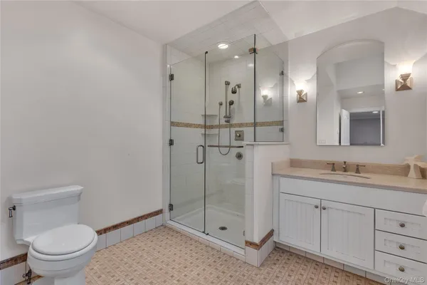 a bathroom with a toilet a sink shower and mirror