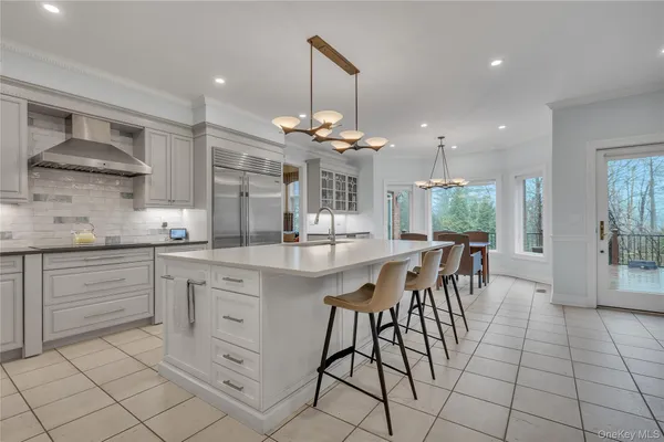 a kitchen with stainless steel appliances kitchen island granite countertop a table chairs sink and cabinets