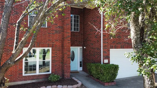 a view of a brick house with a plants and a tree