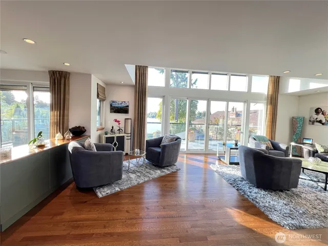 a living room with furniture large windows and wooden floor