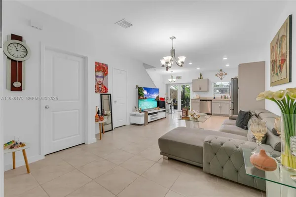 a living room with furniture a chandelier and a flat screen tv