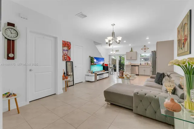 a living room with furniture a chandelier and a flat screen tv