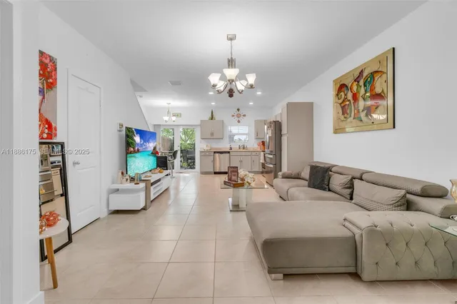 a living room with furniture kitchen view and a chandelier