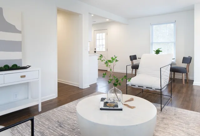 a dining room with wooden floor white walls and a chandelier