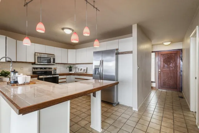 a kitchen with stainless steel appliances granite countertop a sink a stove a refrigerator cabinets and living room view