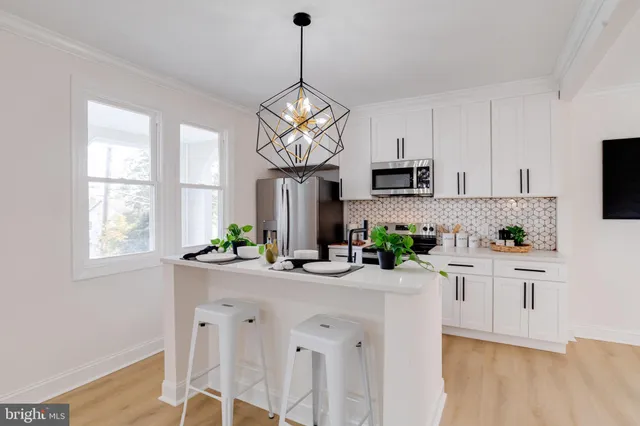a kitchen with stainless steel appliances a white table chairs and a window