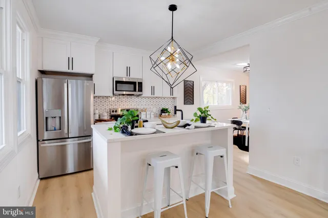 a kitchen with stainless steel appliances kitchen island granite countertop a refrigerator a microwave a stove and a refrigerator