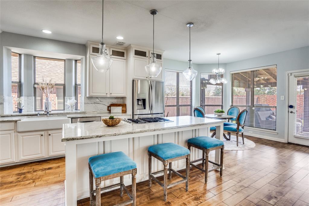 1804 Goodnight Lane Allen, TX 75002 - Photo 16 of 35 Kitchen featuring backsplash, a breakfast bar area, stainless steel appliances, white cabinets, and a center island
