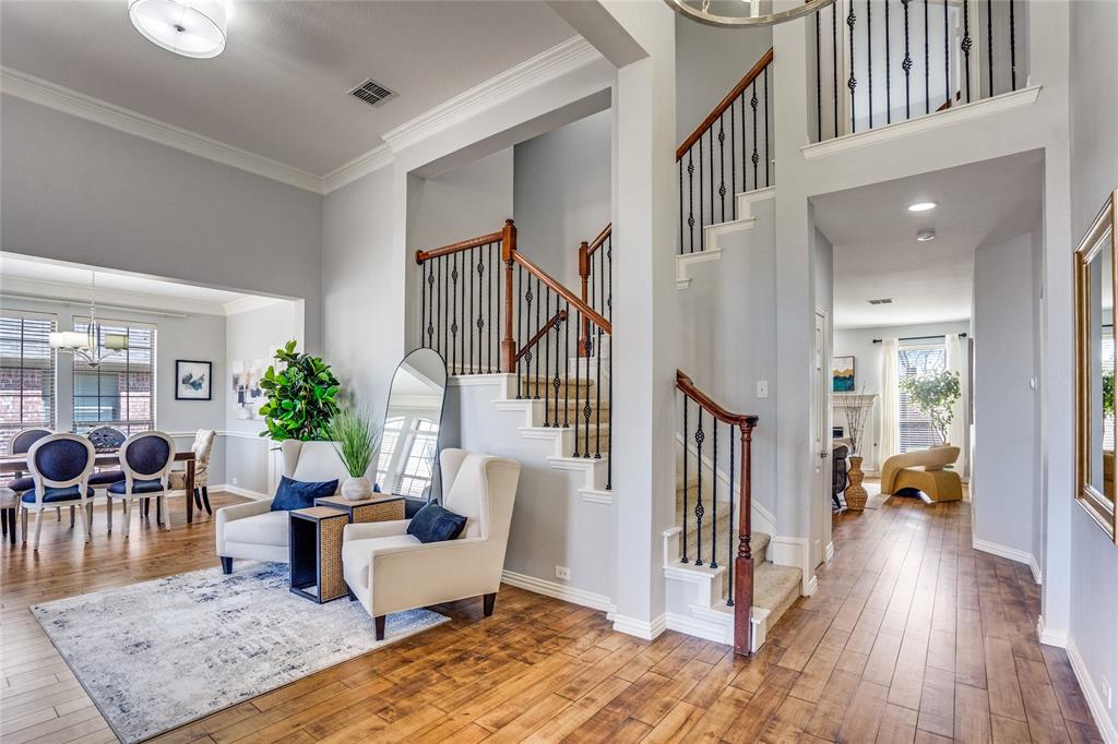 1804 Goodnight Lane Allen, TX 75002 - Photo 6 of 35 Entryway with solid hardwood flooring, a fireplace, crown molding, a chandelier, and a high ceiling